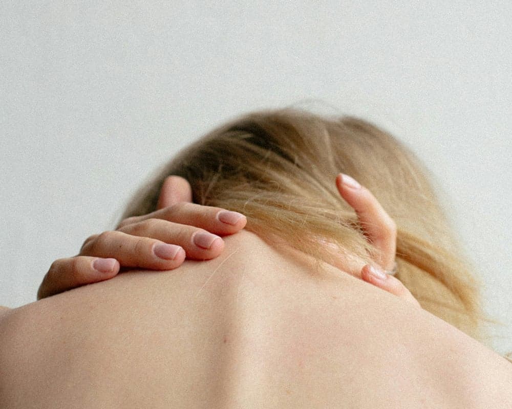 Person holding the back of their neck. Tech neck relief at Thera Performance Lab in Lake Orion, MI
